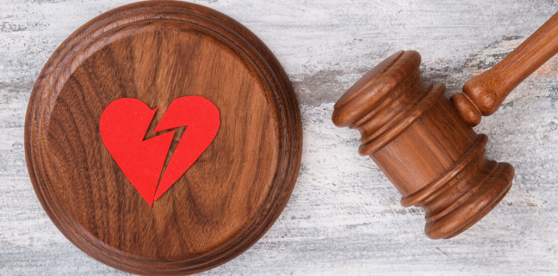 A judge's gavel with a red paper broken heart.