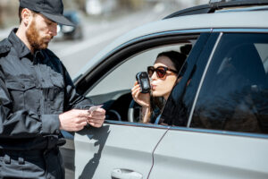 Une femme dans sa voiture soufflant dans un appareil de détection approuvé (ADA), suggère une possible conduite avec facultés affaiblies.