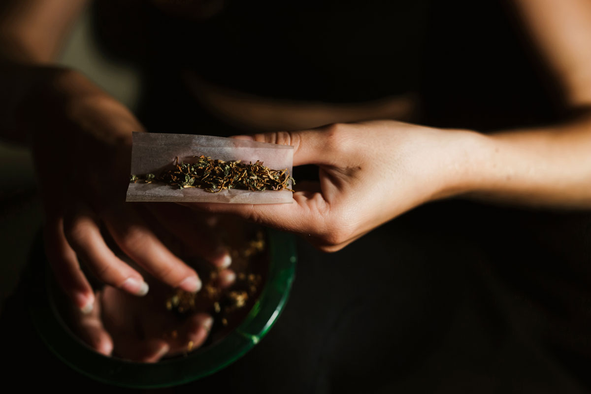 Young woman rolling a joint, symbolizing the risk of impaired driving.