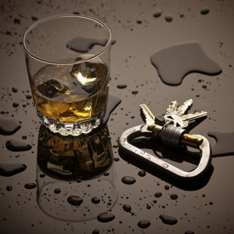 Un verre d'alcool à côté des clés de voiture, suggérant une infraction d'alcool au volant.