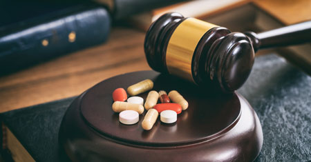 Drugs on a judge's gavel, suggesting the need for a drug crime lawyer.