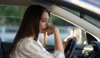 A worried woman behind the wheel, suggesting an impaired driving offence.