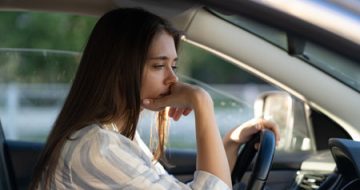 A worried woman behind the wheel, suggesting an impaired driving offence.